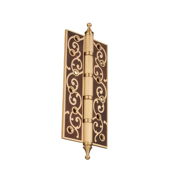 "Brown and brass door hinge with ornate scrollwork design, isolated on a white background."