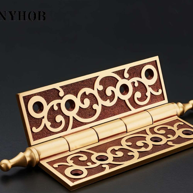 "Open brass door hinge with ornate scrollwork design, showcasing the detailed craftsmanship."