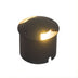 Black cylindrical in-ground outdoor light with warm illuminated opening on white background.