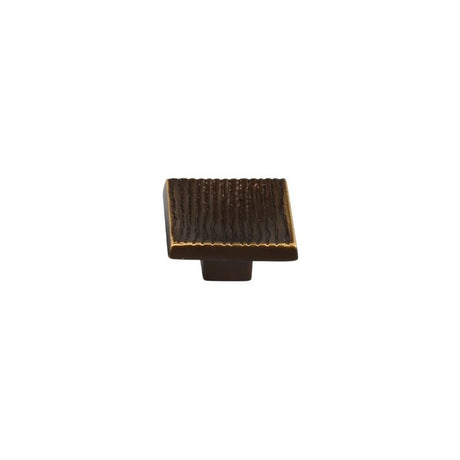 "Studio shot of a single dark bronze square cabinet knob with a ridged, textured surface on a white background."