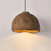 Dome pendant light in aged bronze with warm golden interior glow against white background.