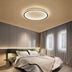 Modern oval LED ceiling light with black trim and warm white glow in a contemporary bedroom setting.