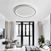 Modern oval LED ceiling light with gray metal frame mounted in contemporary bedroom with white walls and black furnishings.
