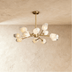 Gold branching chandelier with frosted glass shades against dark blue paneled wall above gray sofa.