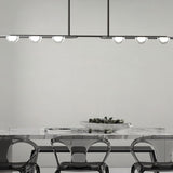 "Copper Dilti pendant light with glass globes hanging above a dining table with transparent chairs."