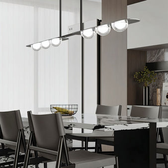 "Copper Dilti pendant light with glass globes hanging above a dining table with grey chairs."