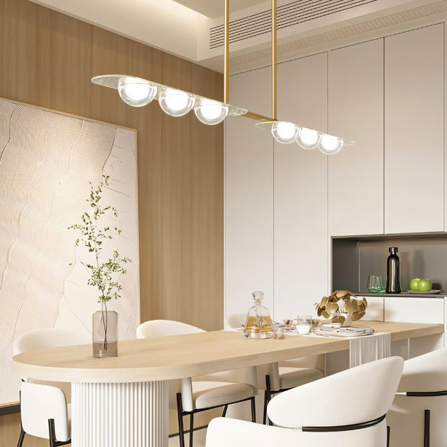 "Modern linear pendant light with copper frame and clear glass globes hanging above a dining table."