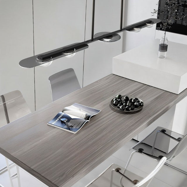 "Modern linear pendant light with silver frame and clear glass globes hanging above a dining table."