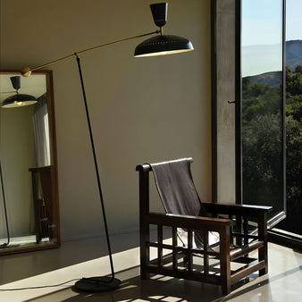 "Diona floor lamp with adjustable arm, black and gold finish, aluminum and iron material, featured in a living room setting next to a modern wooden chair"