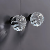"Two clear crystal glass spherical knobs with ribbed texture on a gray cabinet."