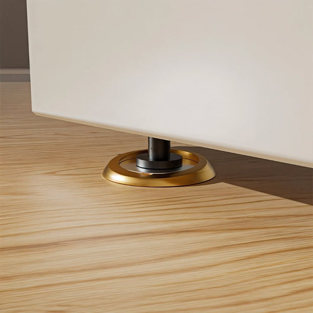 "Gold magnetic door stop installed on a light wood floor, holding a door ajar."