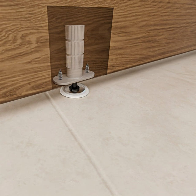 "White magnetic door stop installed on a baseboard with wood trim, against a light-colored floor."