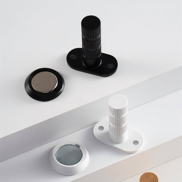 "Modern black and white magnetic door stops with textured cylindrical posts and oval bases."