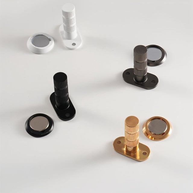 "Magnetic door stops in white, black, brushed nickel, and gold finishes with separate base plates."