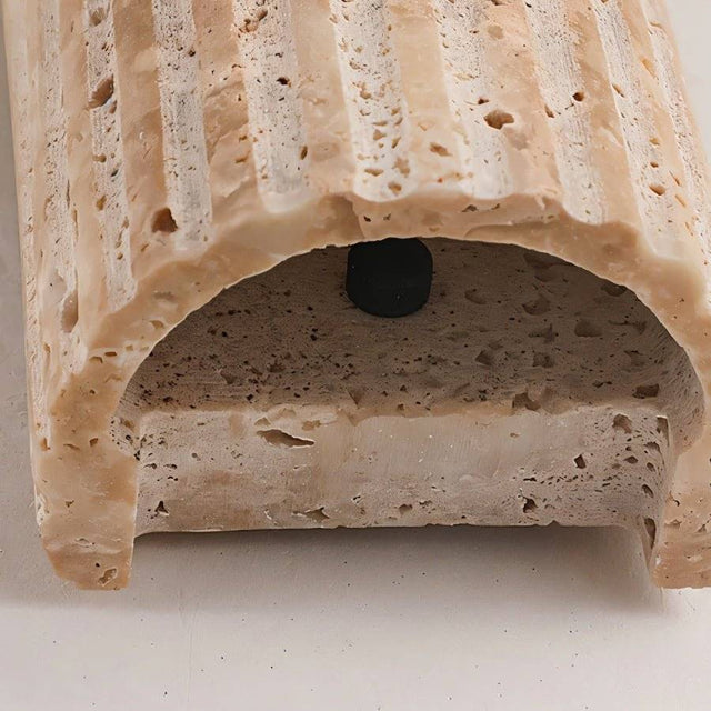 "Close-up detail of a minimalist, rectangular travertine wall lamp, showcasing the natural stone texture and craftsmanship."
