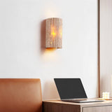 "A minimalist, rectangular travertine wall lamp mounted on a white wall in a home office, providing a soft, focused light above a desk with a laptop."