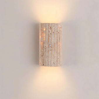 "A minimalist, rectangular wall lamp crafted from travertine, mounted on a light-colored wall, emitting a soft, ambient glow."