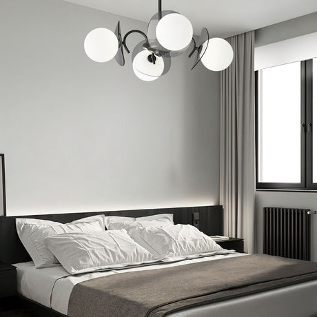 "Copper Dyana chandelier with frosted glass globes hanging above a bed with white pillows and a grey throw."