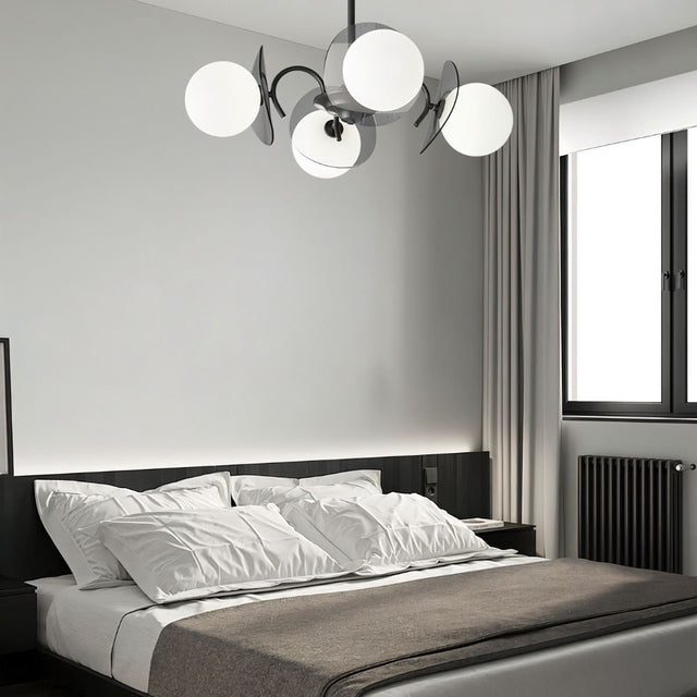 "Copper Dyana chandelier with frosted glass globes hanging above a bed with white pillows and a grey throw."