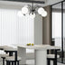 "Copper Dyana chandelier with frosted glass globes hanging above a white dining table with chairs."