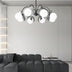 "Copper Dyana chandelier with frosted glass globes hanging above a modern living room with a grey sectional sofa."