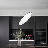 "A disc-shaped pendant light suspended above a kitchen island, providing directional and task lighting."
