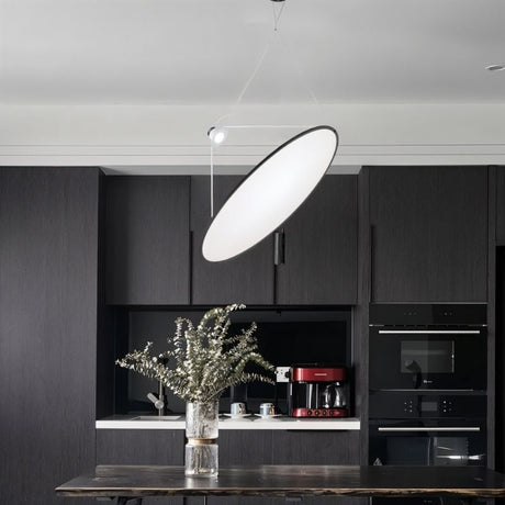 "A disc-shaped pendant light suspended above a kitchen island, providing directional and task lighting."