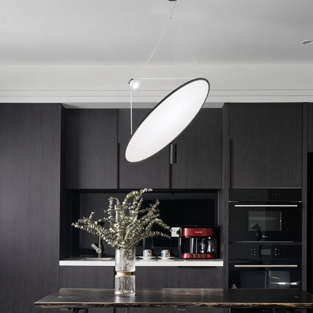 "A disc-shaped pendant light suspended above a kitchen island, providing directional and task lighting."