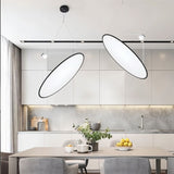 "Two disc-shaped pendant lights suspended above a modern dining table, providing directional and ambient illumination."