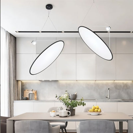 "Two disc-shaped pendant lights suspended above a modern dining table, providing directional and ambient illumination."