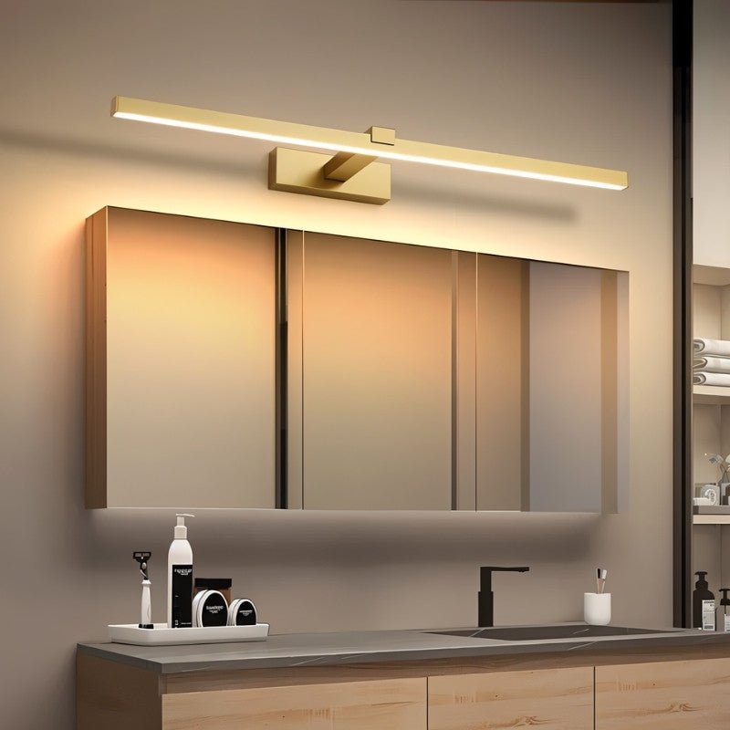 "A modern, gold LED wall lamp illuminating a bathroom vanity with a mirror and countertop."