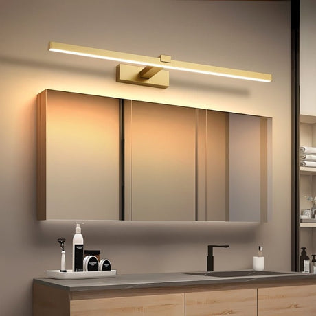"A modern, gold LED wall lamp illuminating a bathroom vanity with a mirror and countertop."