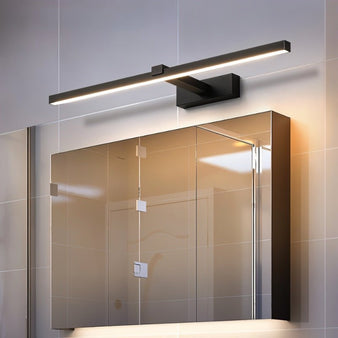 "A modern, dark finish LED wall lamp illuminating a bathroom mirror with a tiled wall."