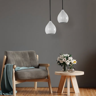 "Modern white pendant lights with teardrop-shaped ceramic shades in a living room with grey walls, a grey armchair, and a side table with flowers."