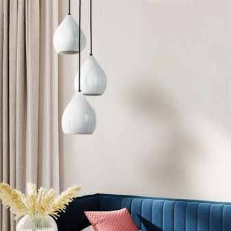 "Modern white pendant lights with teardrop-shaped ceramic shades in a minimalist living room with a blue sofa and a glass vase with pampas grass."