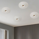 "Four white ceiling lights with concentric circles, installed flush in a white ceiling of a modern room with gray walls and a window."