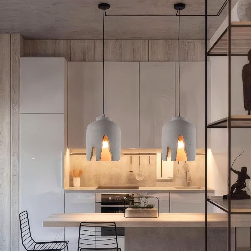 "Modern concrete pendant lights hanging over a kitchen island, featuring sculptural industrial design with warm lighting"