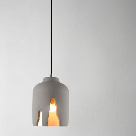 "Concrete pendant light with sculptural cutouts, featuring an industrial modern style and warm illumination"