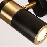 "Close-up of a modern black and gold bedside reading lamp with an adjustable cylindrical spotlight, showcasing the metallic joint and focused light."