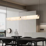 "Linear alabaster pendant light with natural veining over a dining table"
