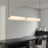 "Linear alabaster pendant light with natural veining over a kitchen island"