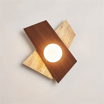 "Eldis Wall Lamp showcasing a modern angular design made of travertine and walnut wood, with a round light source, providing a warm and diffused glow."