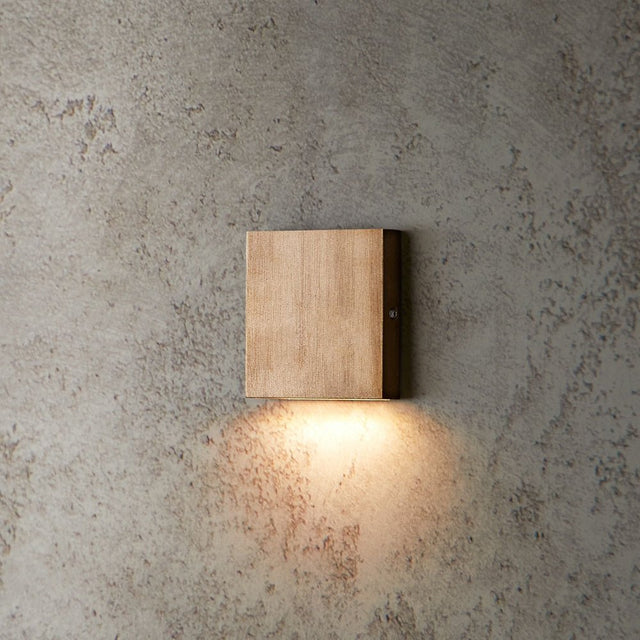 "brass wall lamp, square minimalist design, warm light on textured wall"