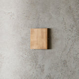 "modern square wall lamp, brass finish, minimalist design on textured wall"