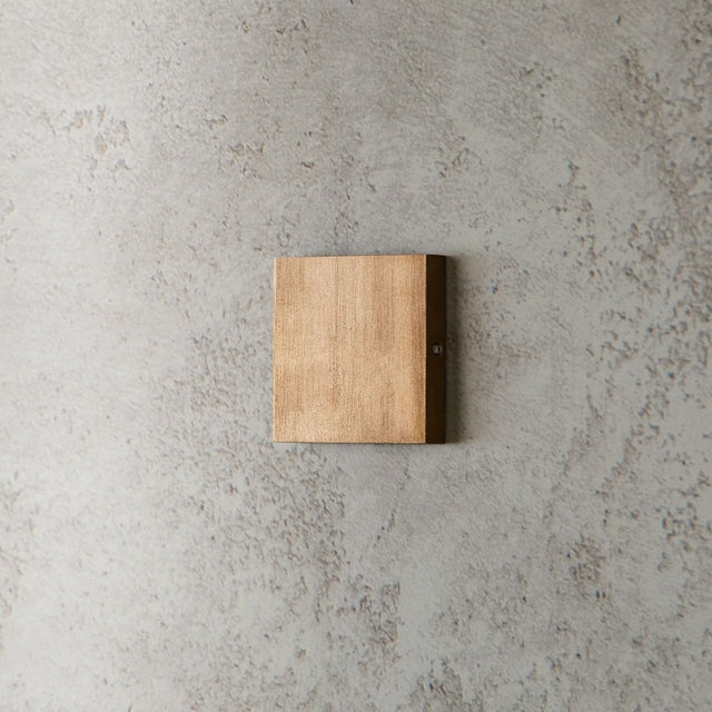 "modern square wall lamp, brass finish, minimalist design on textured wall"