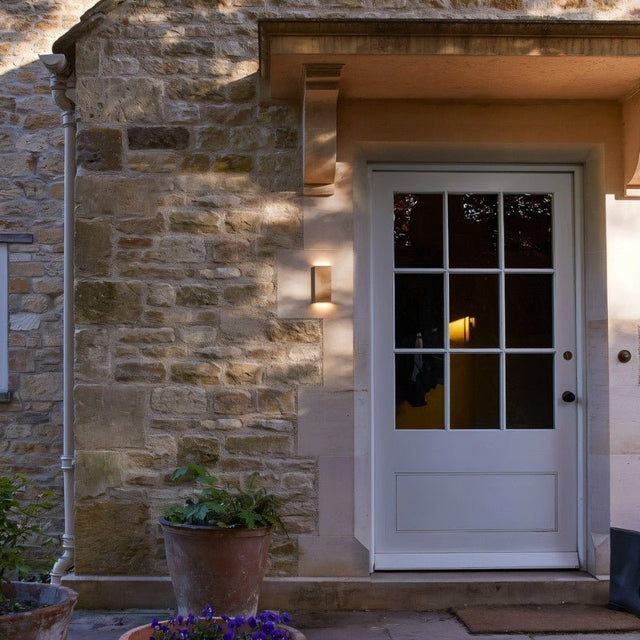 "entryway wall light, brass lamp on stone wall, warm outdoor lighting"