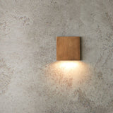 "square brass wall lamp, downward ambient light, minimalist wall fixture"