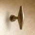 T-shaped knob with oval top handle and cylindrical base, polished finish, white background, front view.
