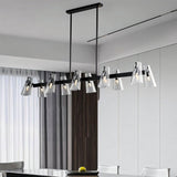 "A linear black brass chandelier with cone-shaped acrylic shades over a dining table."