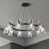 "A modern black brass circular chandelier with cone-shaped acrylic shades on a gray ceiling."